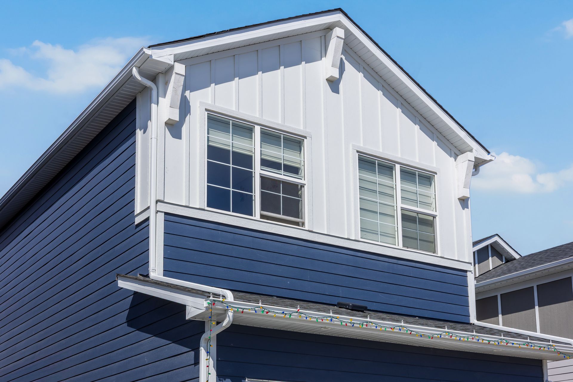 Blue two-story house exterior with white trim and windows against a blue sky