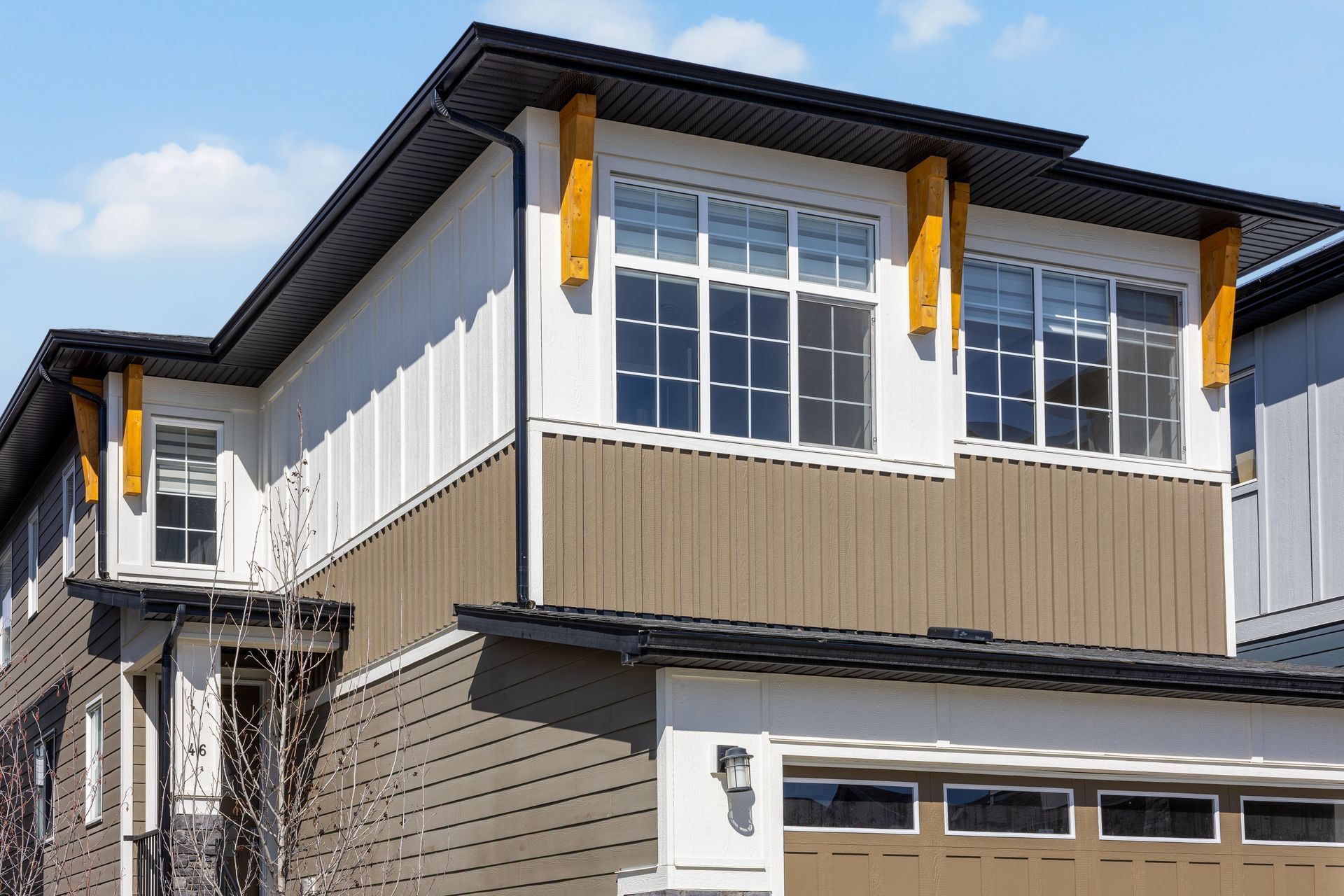 Modern two-story house exterior with gray siding, white trim, and a garage under a blue sky