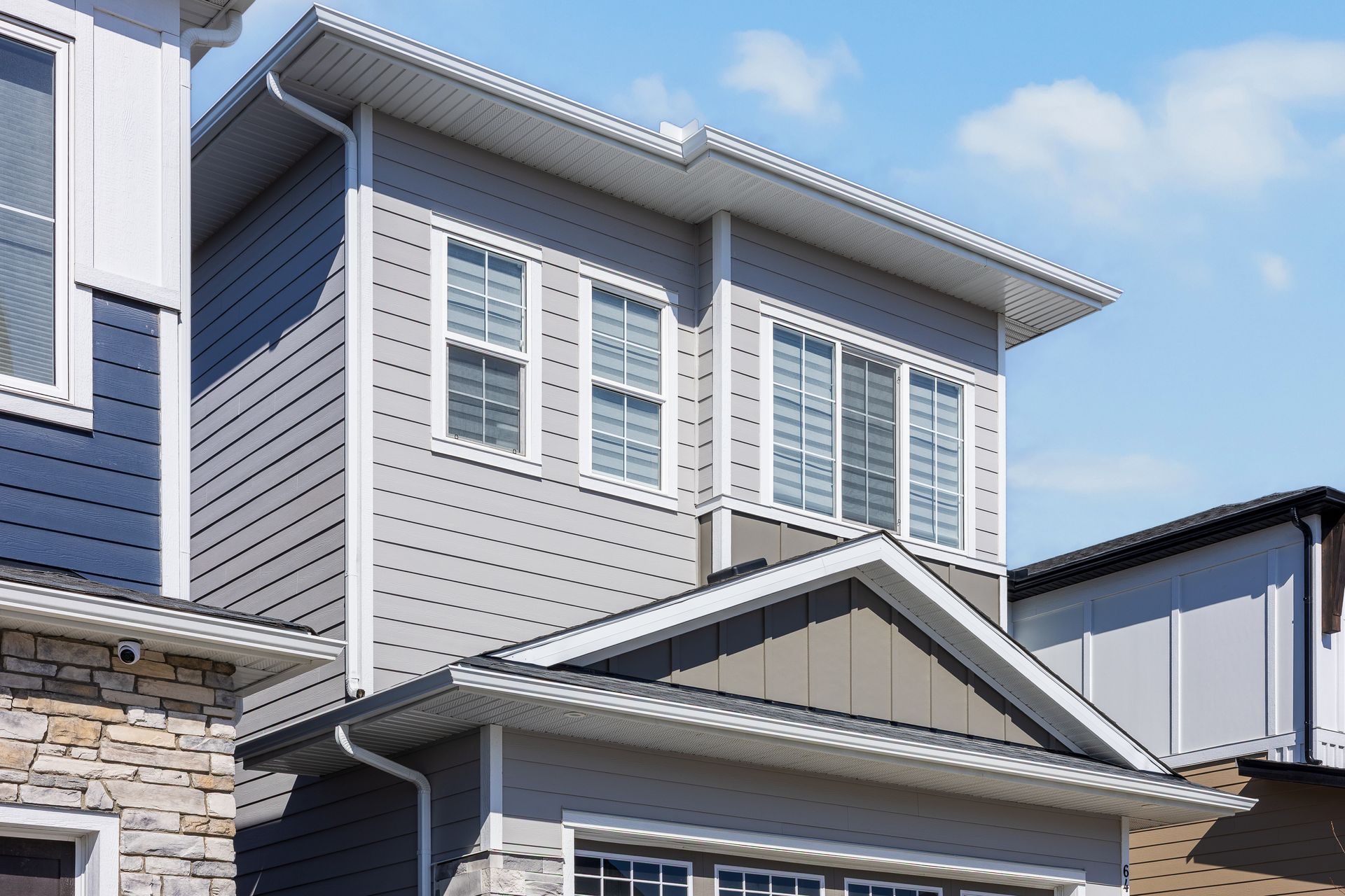 Exterior of a modern gray house with white-trimmed windows and a covered front porch