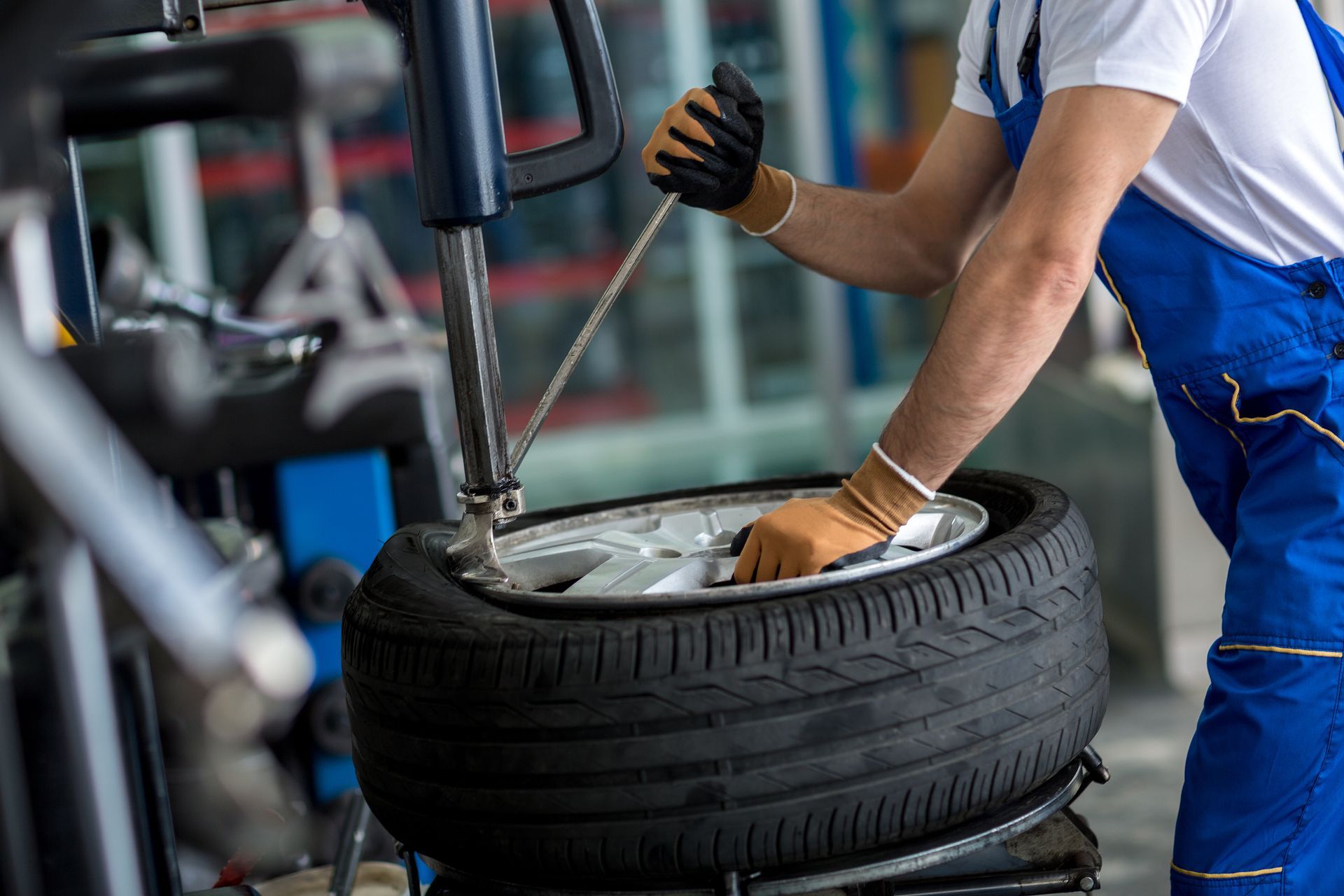 A man is changing a tire on a machine in a garage.