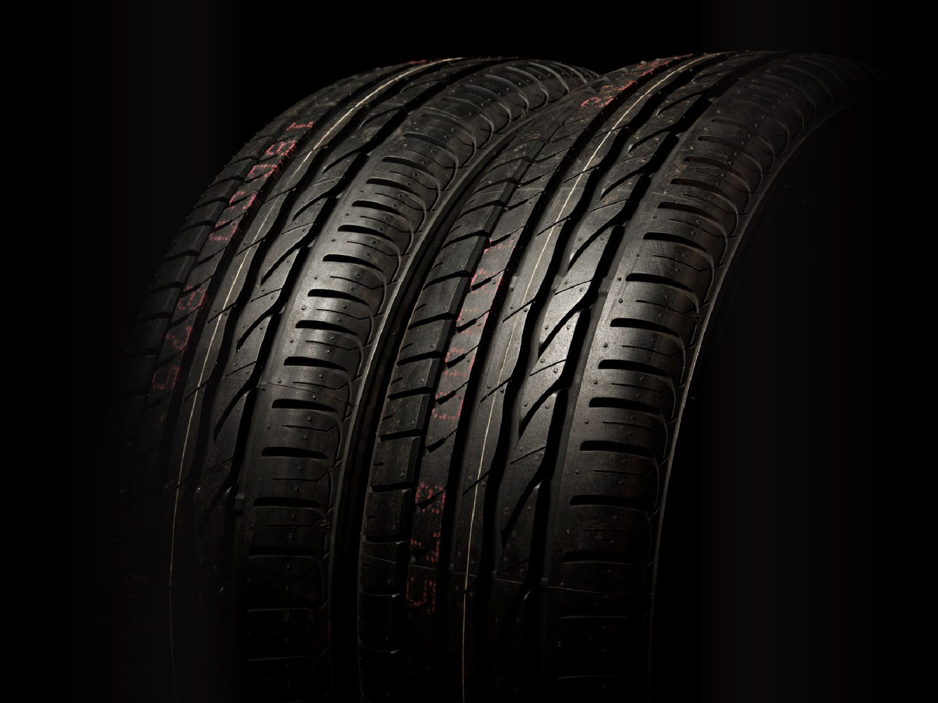 Two black tires are stacked on top of each other on a black background