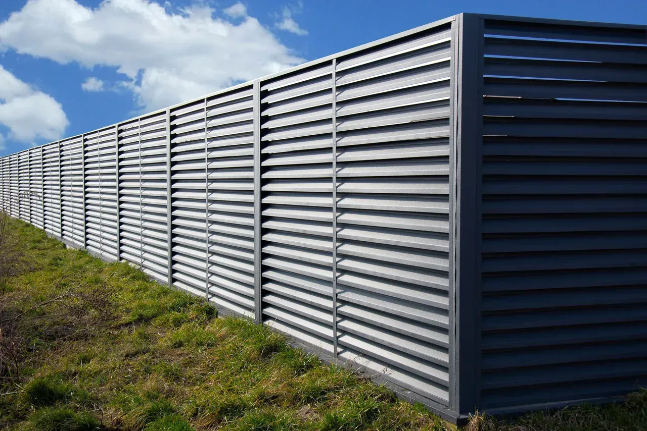 A metal fence is sitting on top of a grassy hill.
