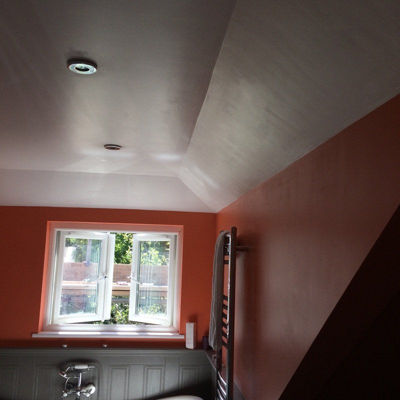 Bathroom with open window, orange walls, sloped ceiling, and towel rack.