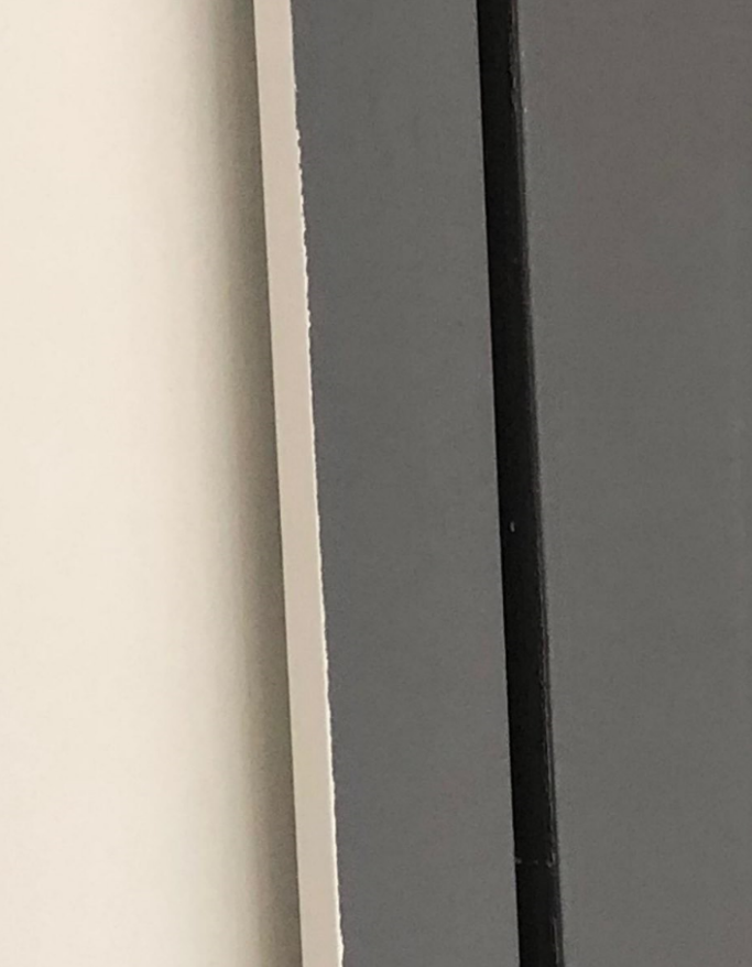 White wall, gray wall, and black vertical bar meet in the frame.