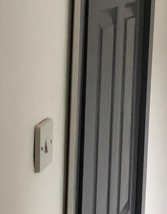 Gray light switch on a white wall next to a gray door.