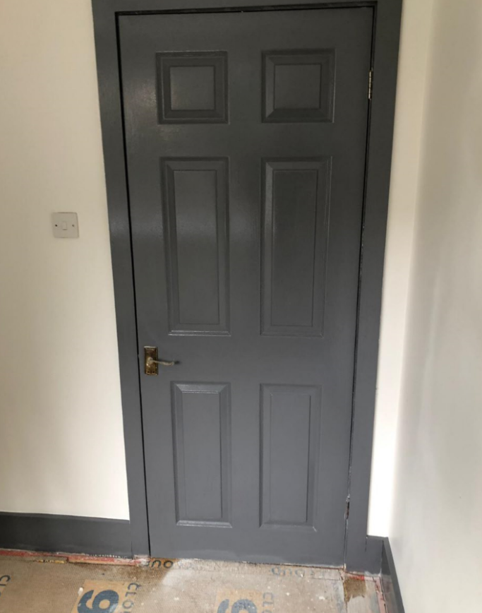 Gray painted six-panel door with matching trim against white walls.