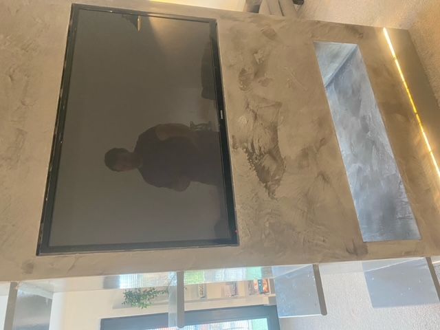 A modern concrete table with a built-in television and a recessed light.
