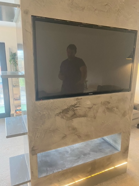 A modern concrete table with a built-in television and a recessed light.