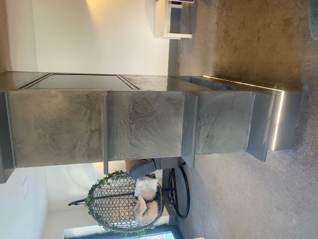Concrete staircase with integrated lighting, leading downwards. A hanging chair sits below.