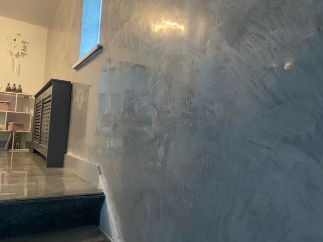 Gray Venetian plaster wall with shiny, mottled finish; steps and window.