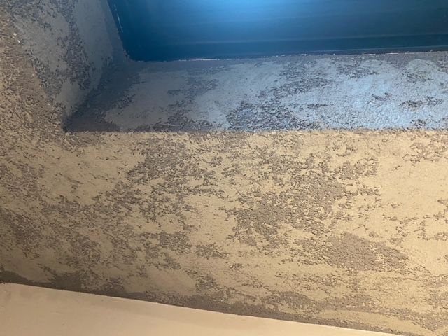 Textured ceiling corner, painted light gray with dark interior recess.