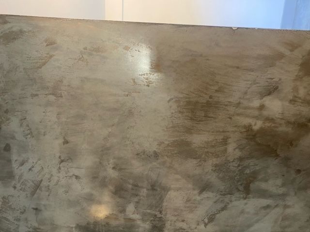 Textured, mottled gray and tan wall with a reflective surface.