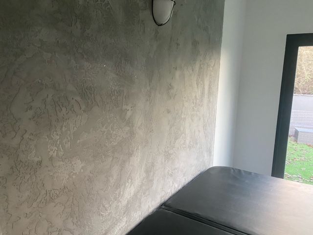 Gray textured wall with a black surface and window in corner.