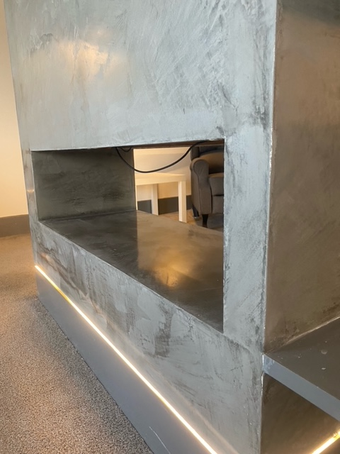 Modern concrete countertop with recessed lighting and a triangular opening.