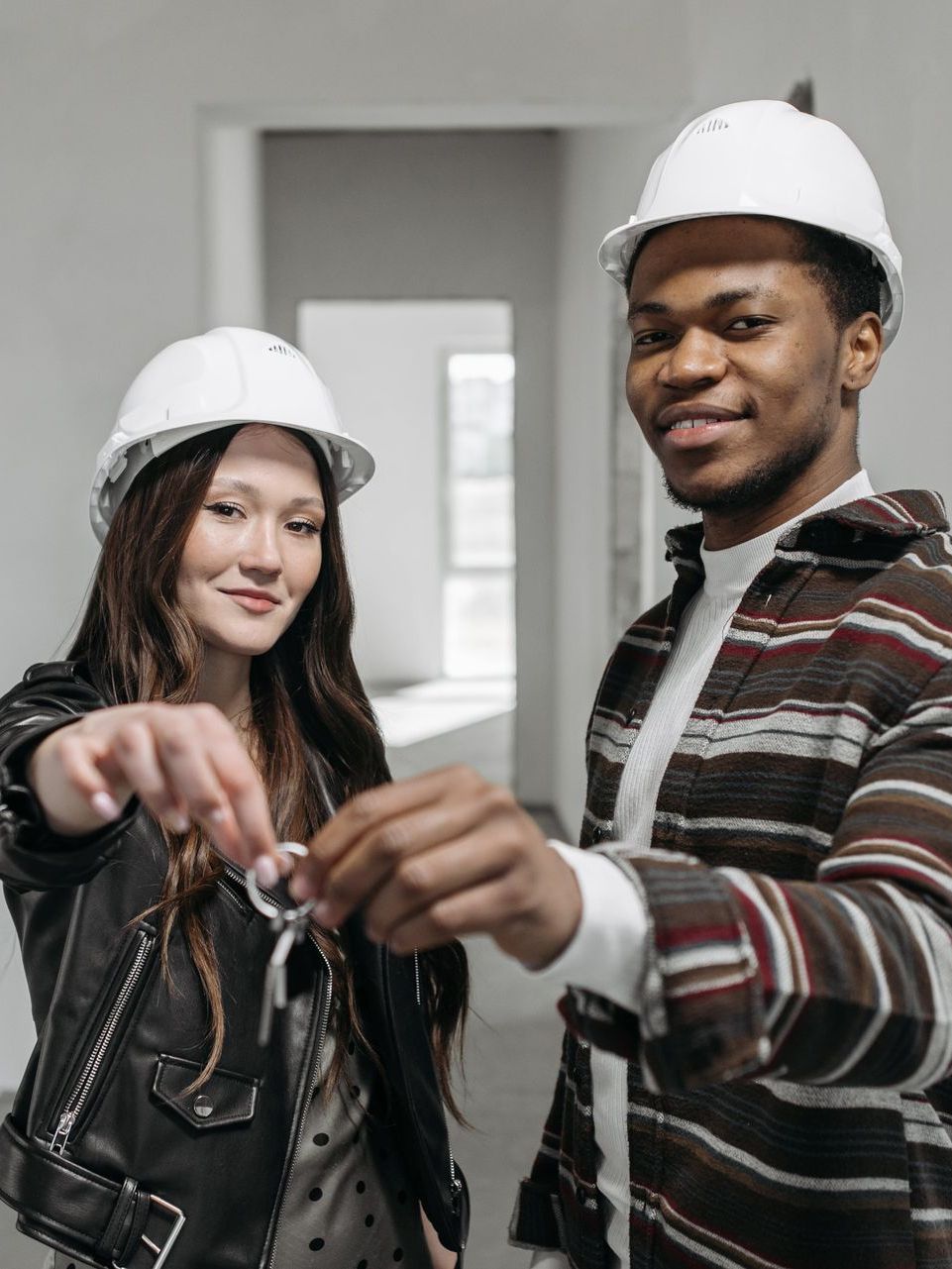 A man and a woman are holding keys to their new home.