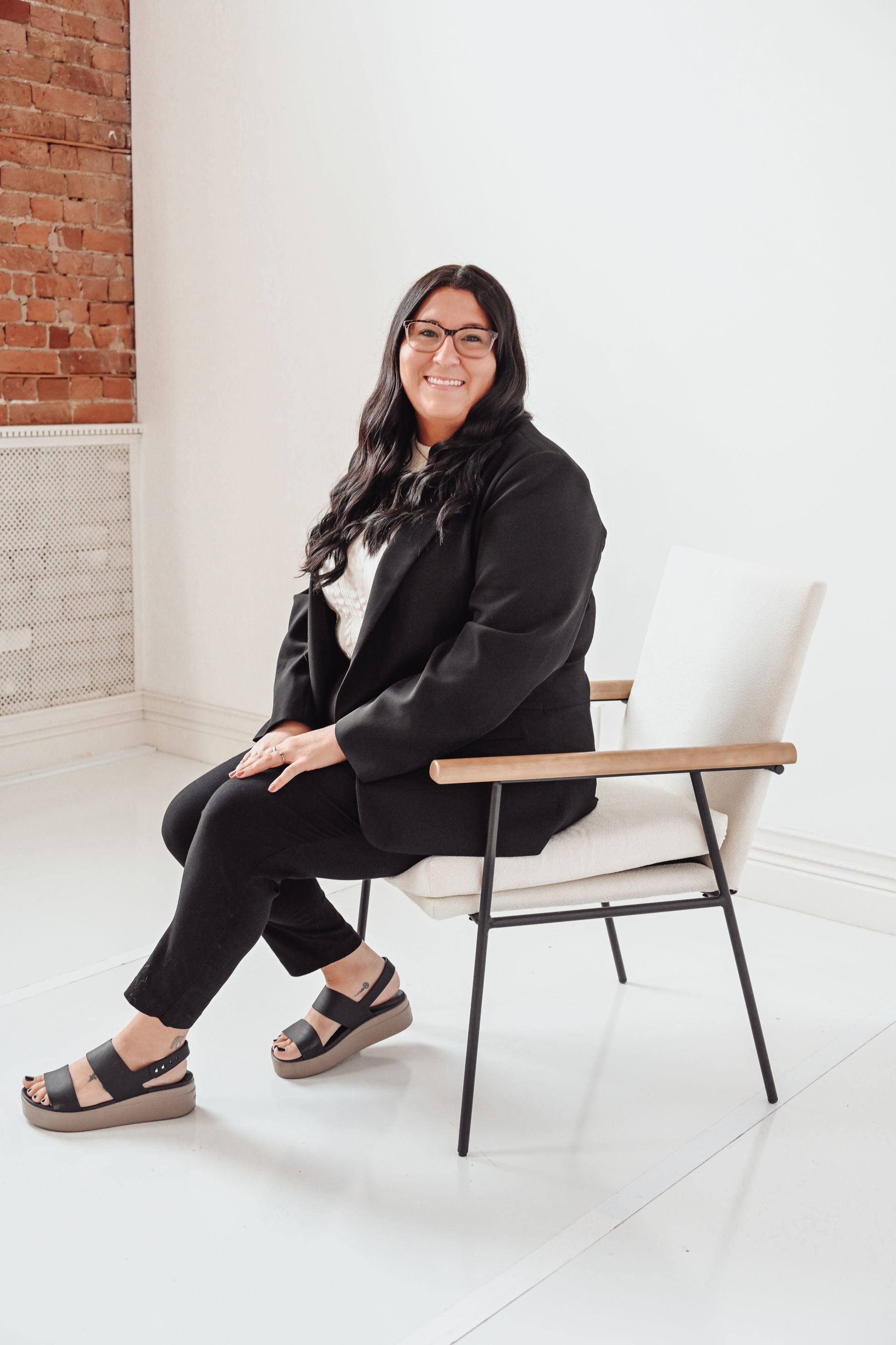 A woman is sitting at a desk with a laptop and a vase of flowers.