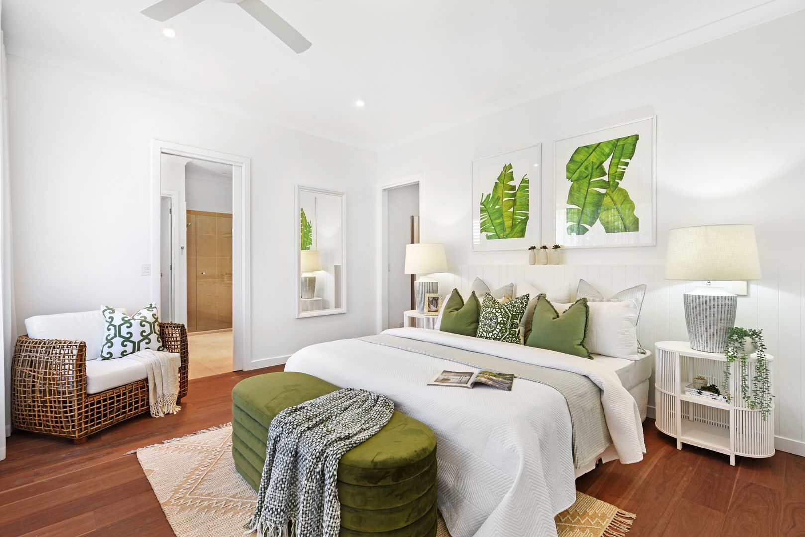 A bedroom with a bed , chair , ottoman and ceiling fan.