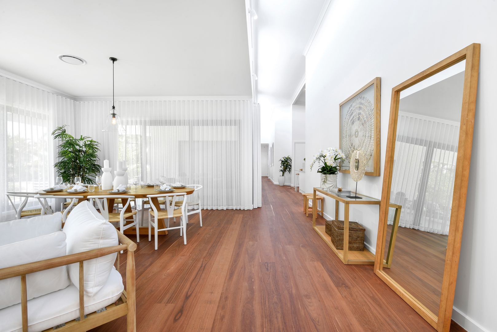 A living room with hardwood floors , a couch , a table and a mirror.