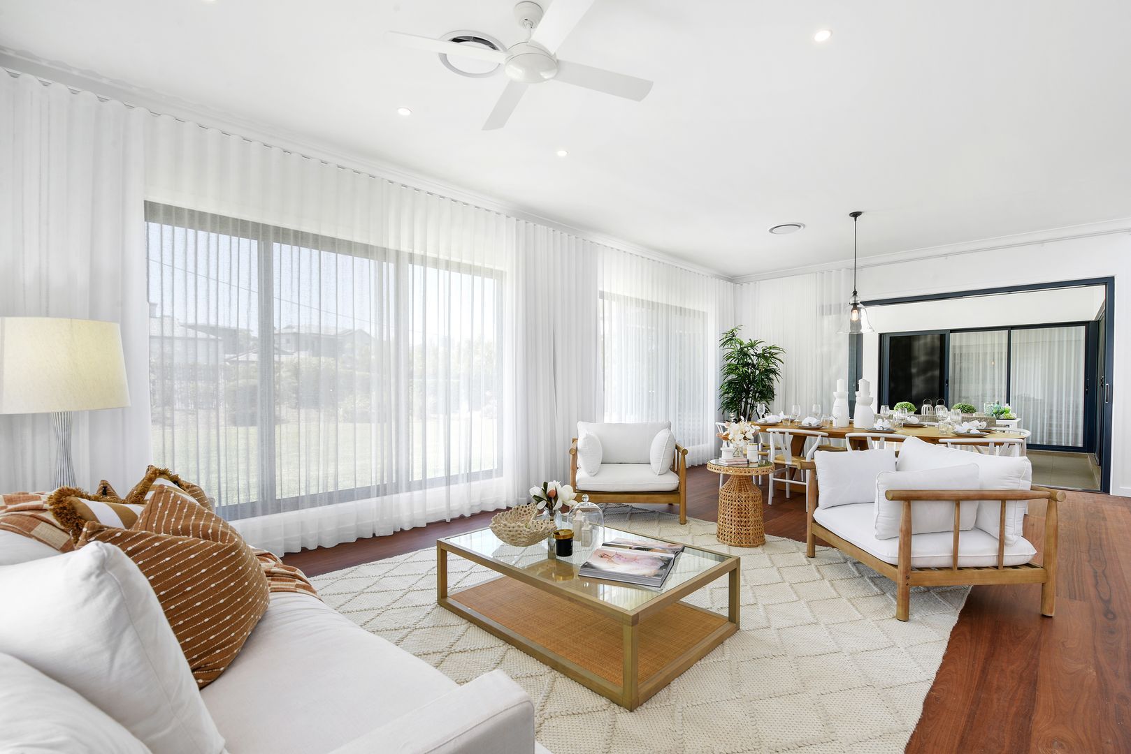 A living room with white furniture and a ceiling fan