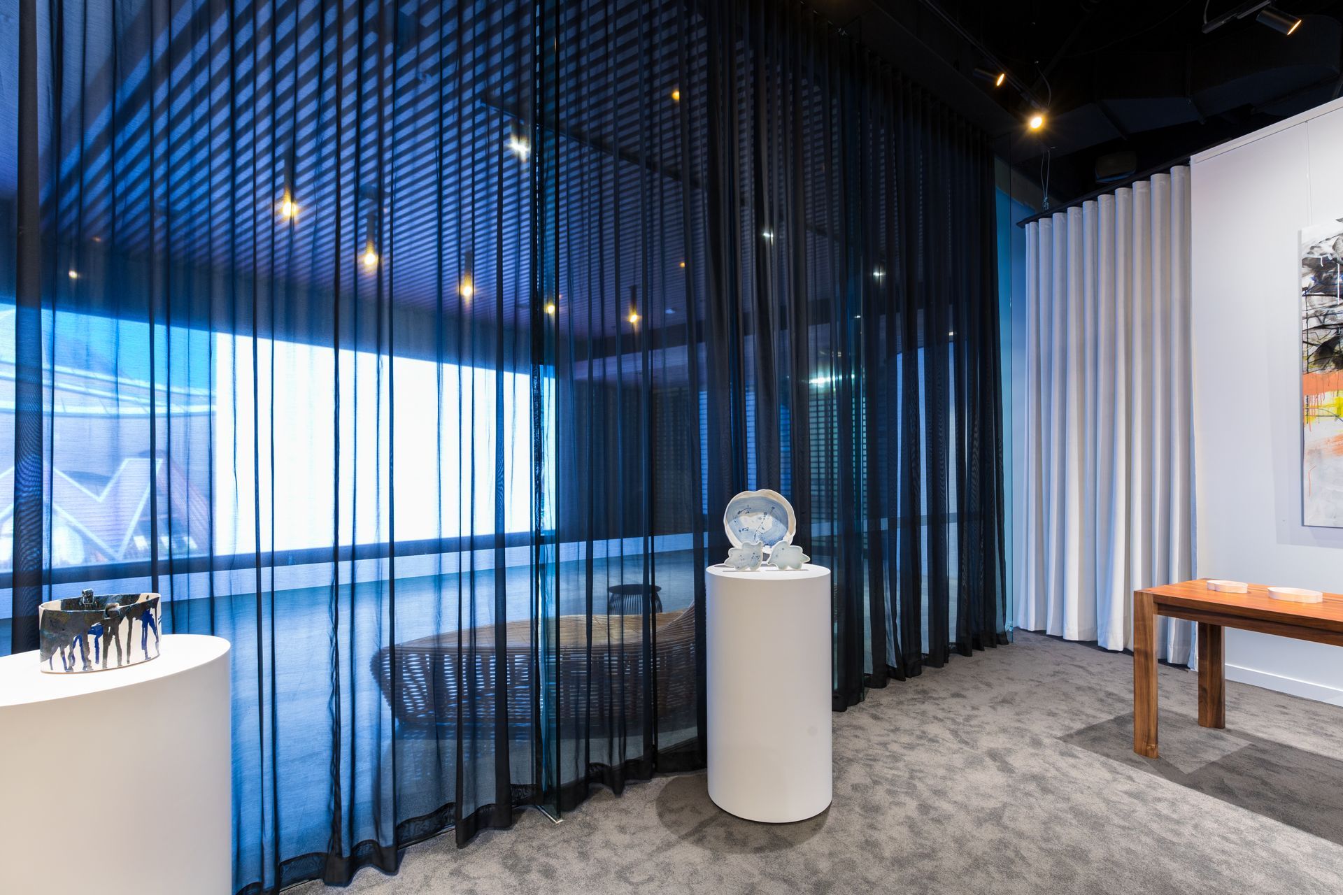 A room with a table and a sculpture on a pedestal in front of a window.