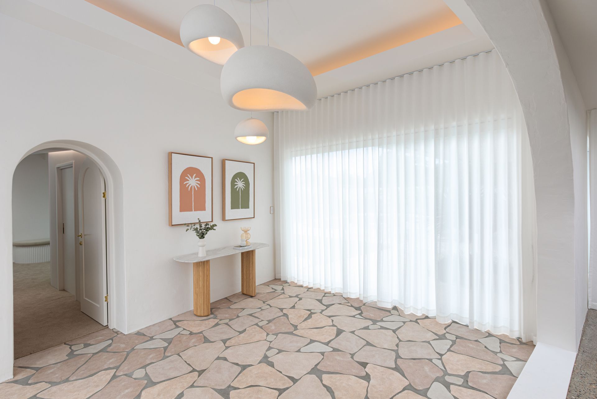 A large room with a stone floor and white curtains.