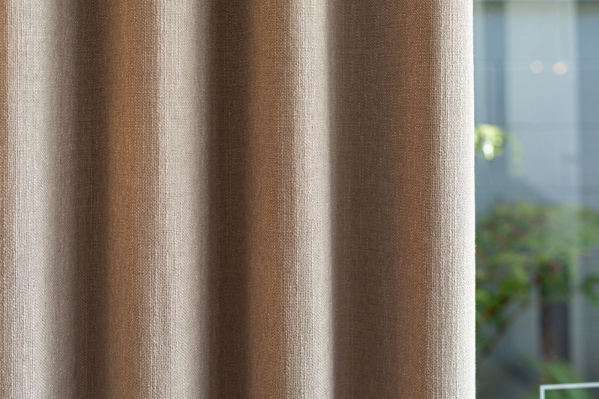 A close up of a brown curtain hanging on a window.