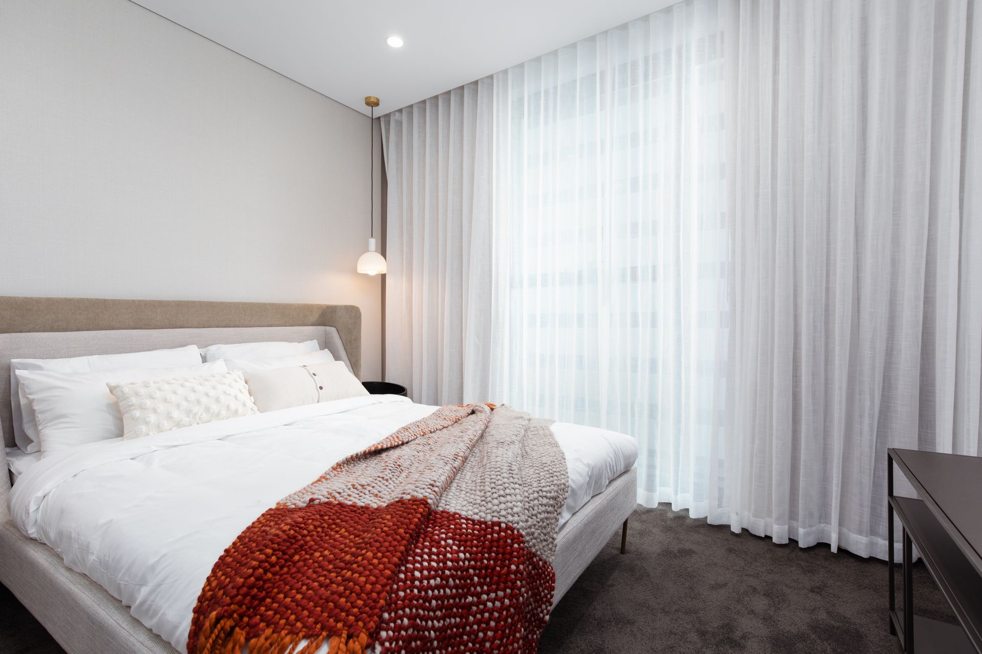 A bedroom with a bed , curtains and a window.