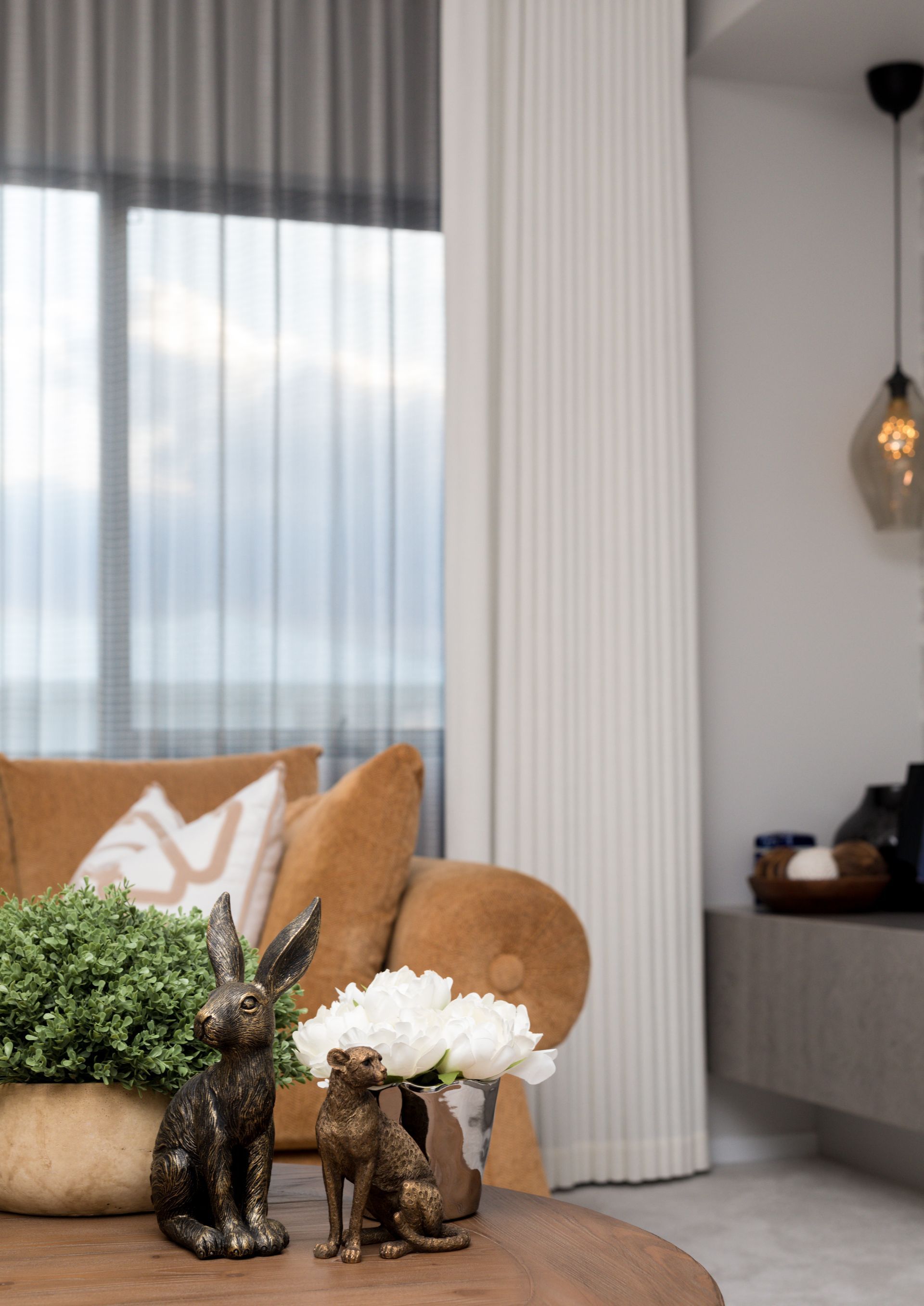 A living room with a couch , a table , and a vase of flowers.