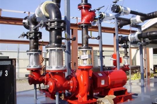 A bunch of red pumps and pipes in a factory