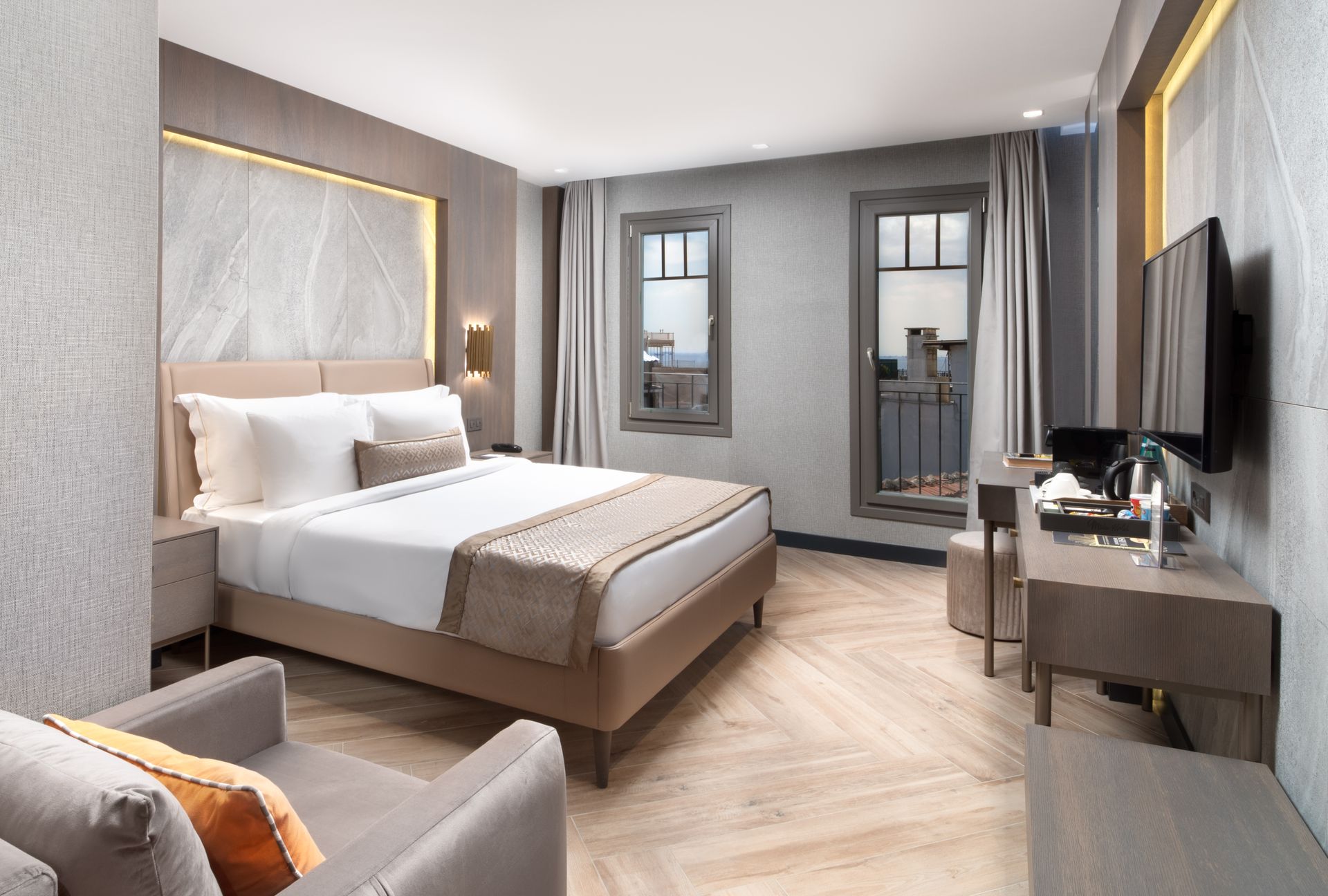 Mula Hotel | Hotel room with a bed, small seating area, desk, and a window overlooking a city view.