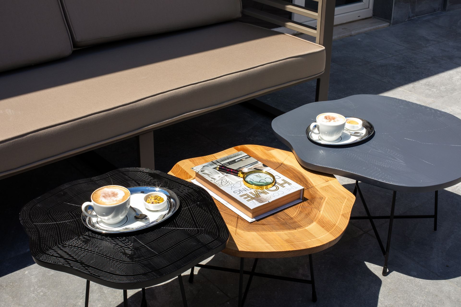 Mula Hotel | Outdoor seating area with coffee, cookies, and books on uniquely shaped side tables.