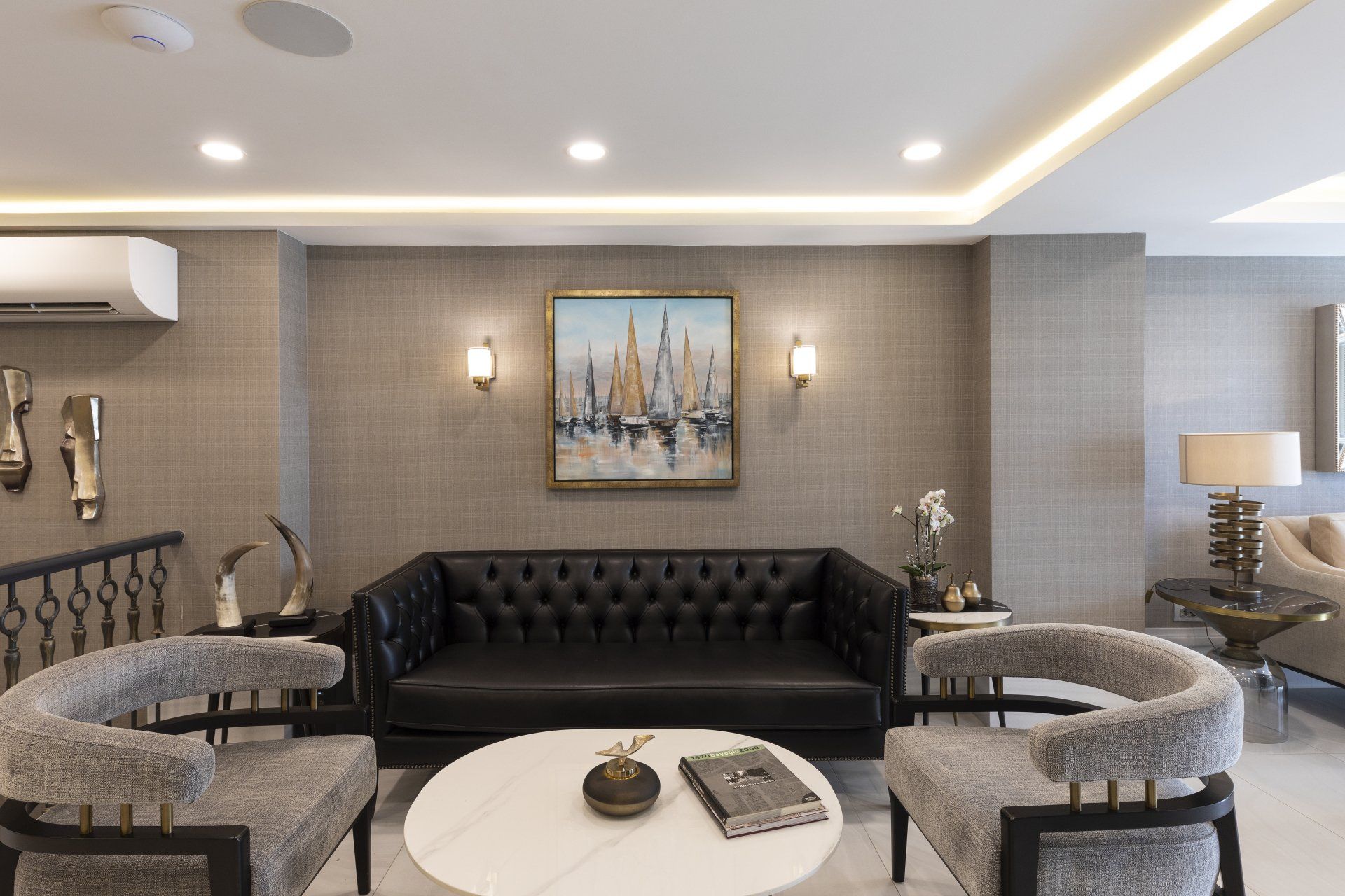 Bir kanepe, sandalyeler, bir masa ve duvarda bir tablo bulunan bir oturma odası.