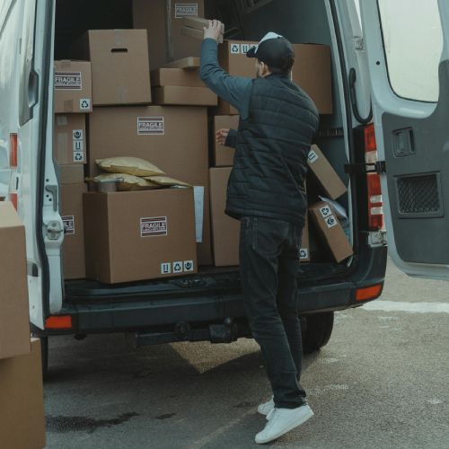 A man is loading boxes into a van that says ' dhl ' on the back
