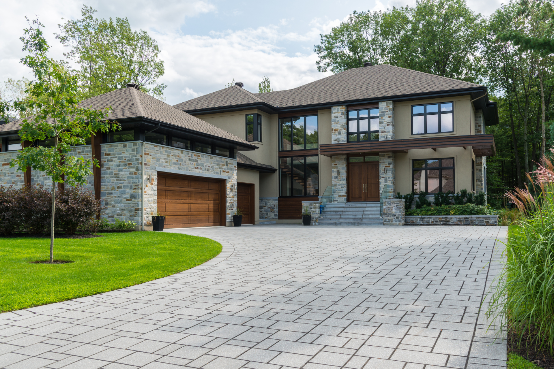 A large custom home with a brick driveway leading to it.