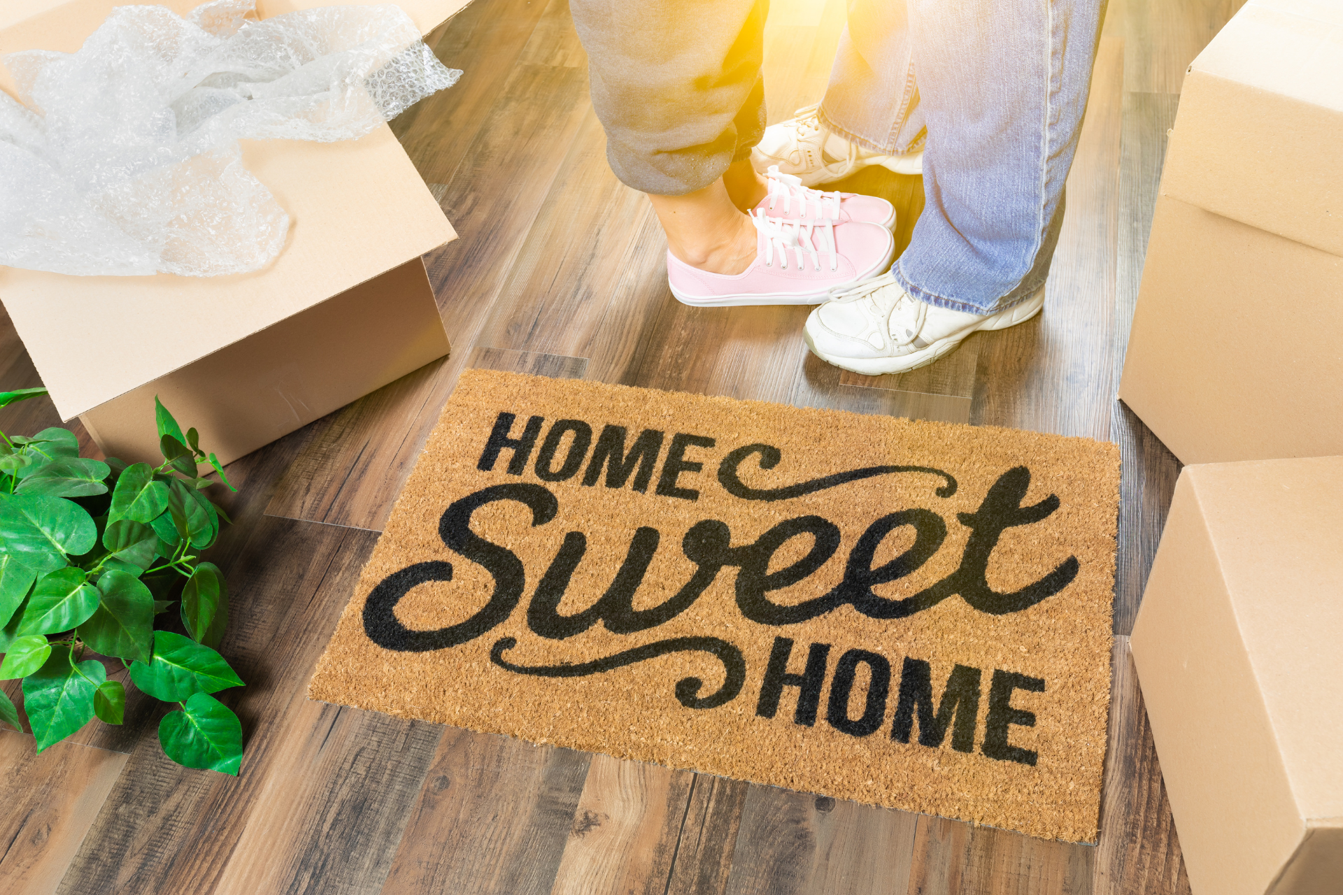 A couple is standing on a door mat that says `` home sweet home ''.
