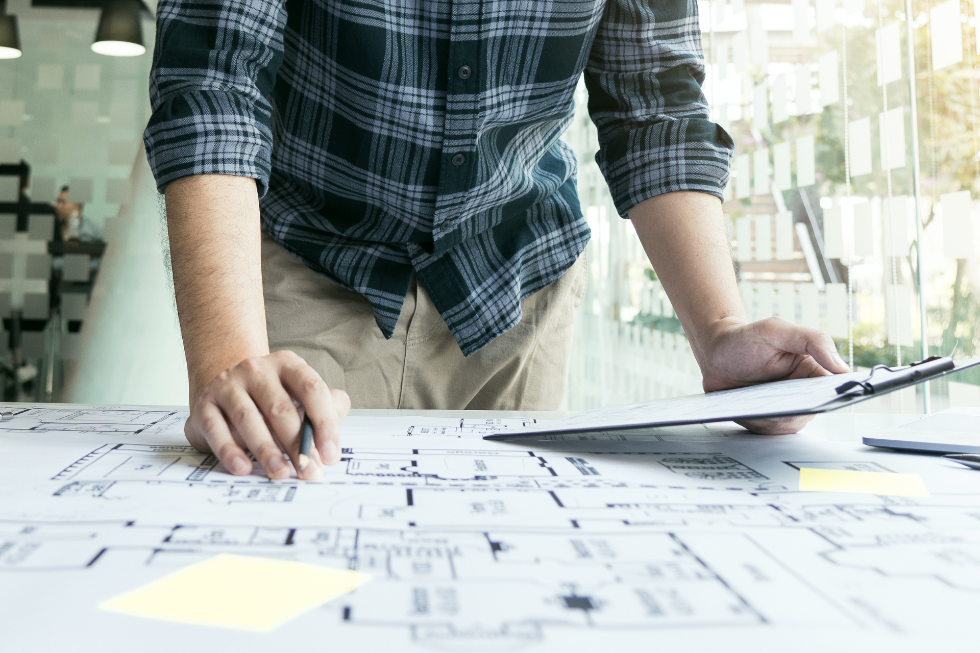 A man is standing at a table looking at a blueprint.