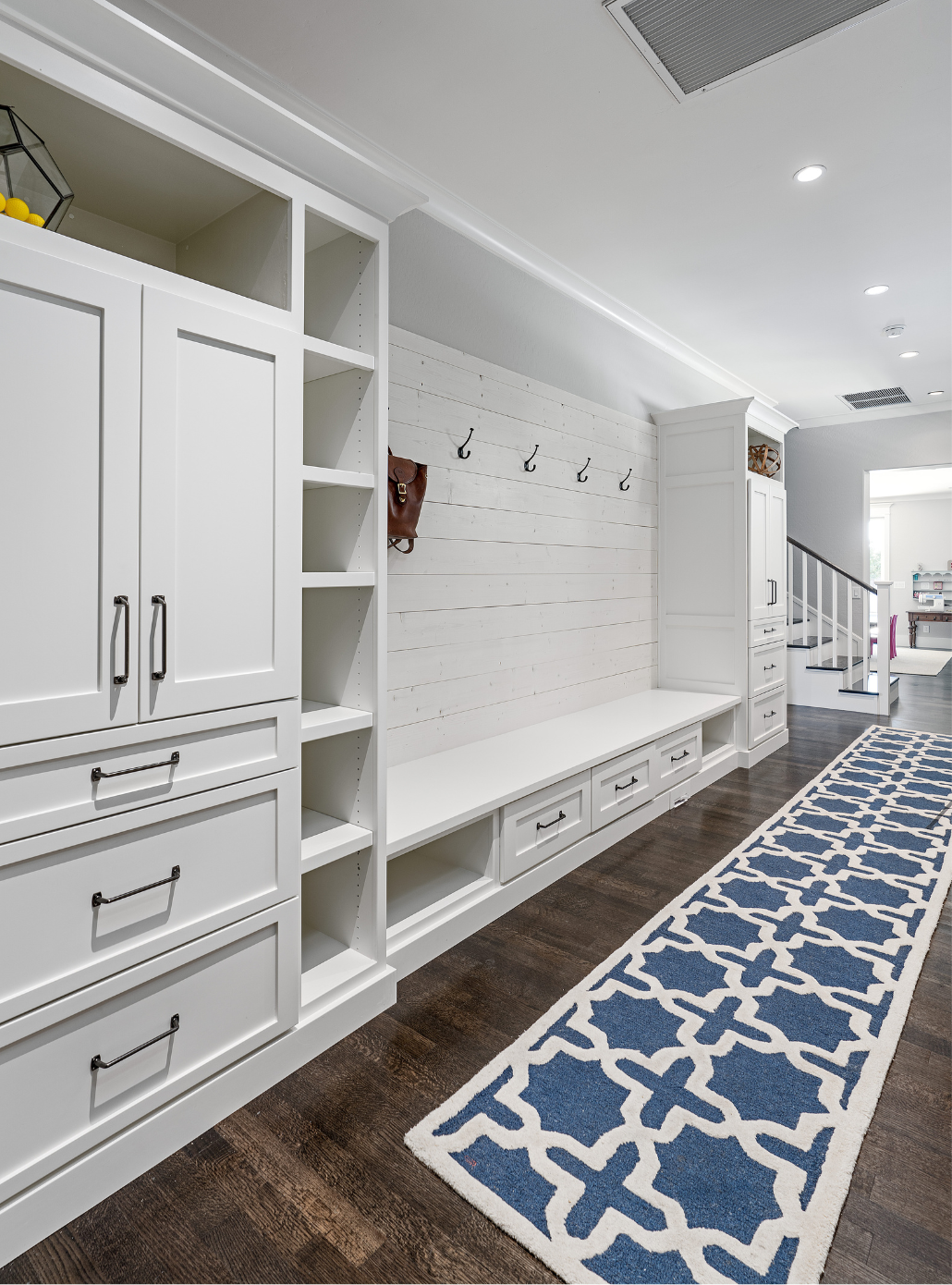 Luxury mudroom area with a blue and white rug in the hallway.