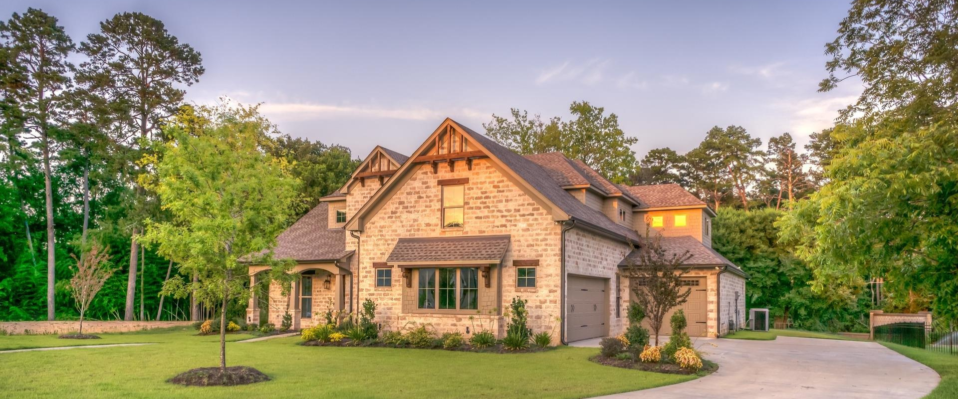 A large house with a driveway leading to it is surrounded by trees.