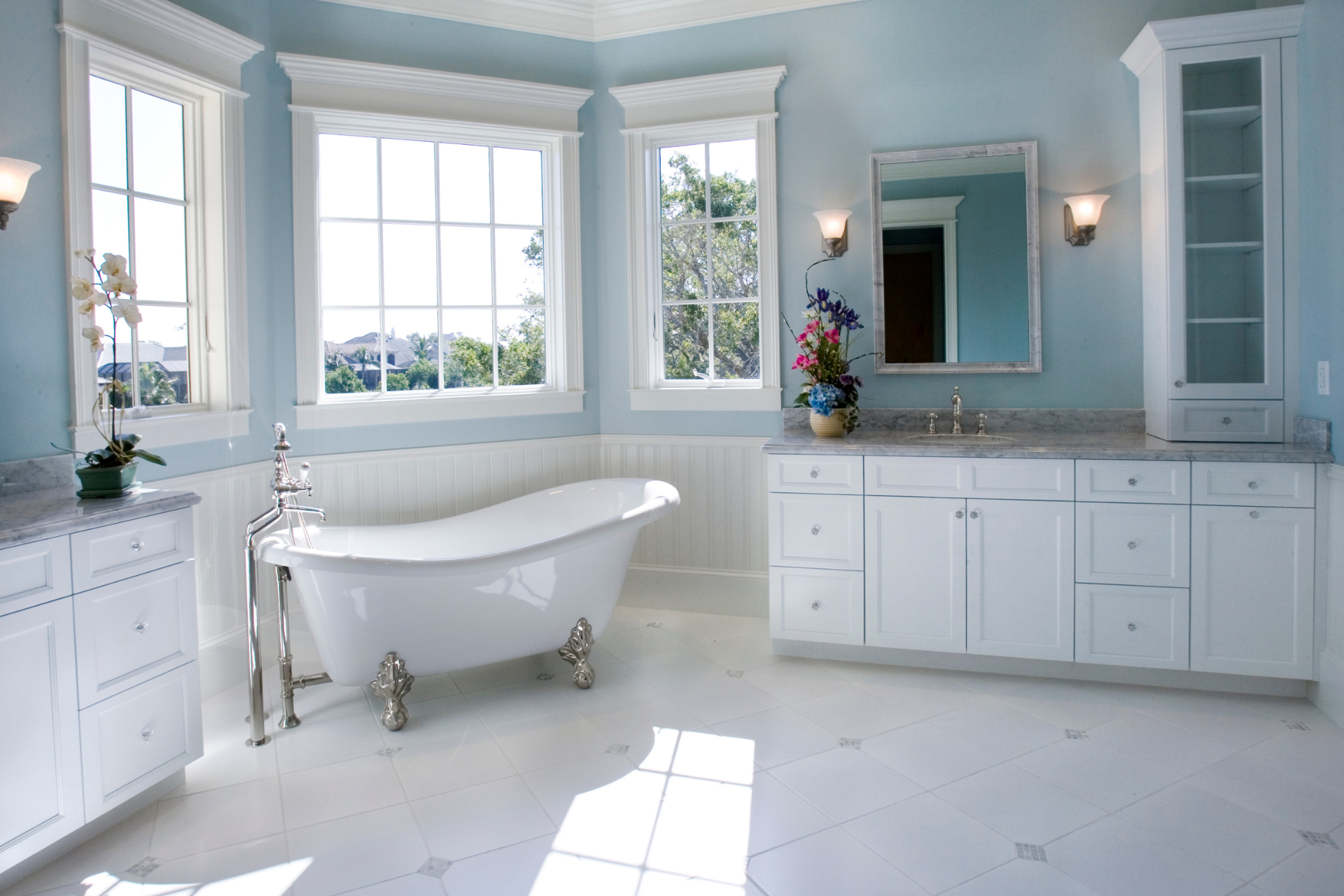 A bathroom with a bathtub, sink, mirror and blue walls.