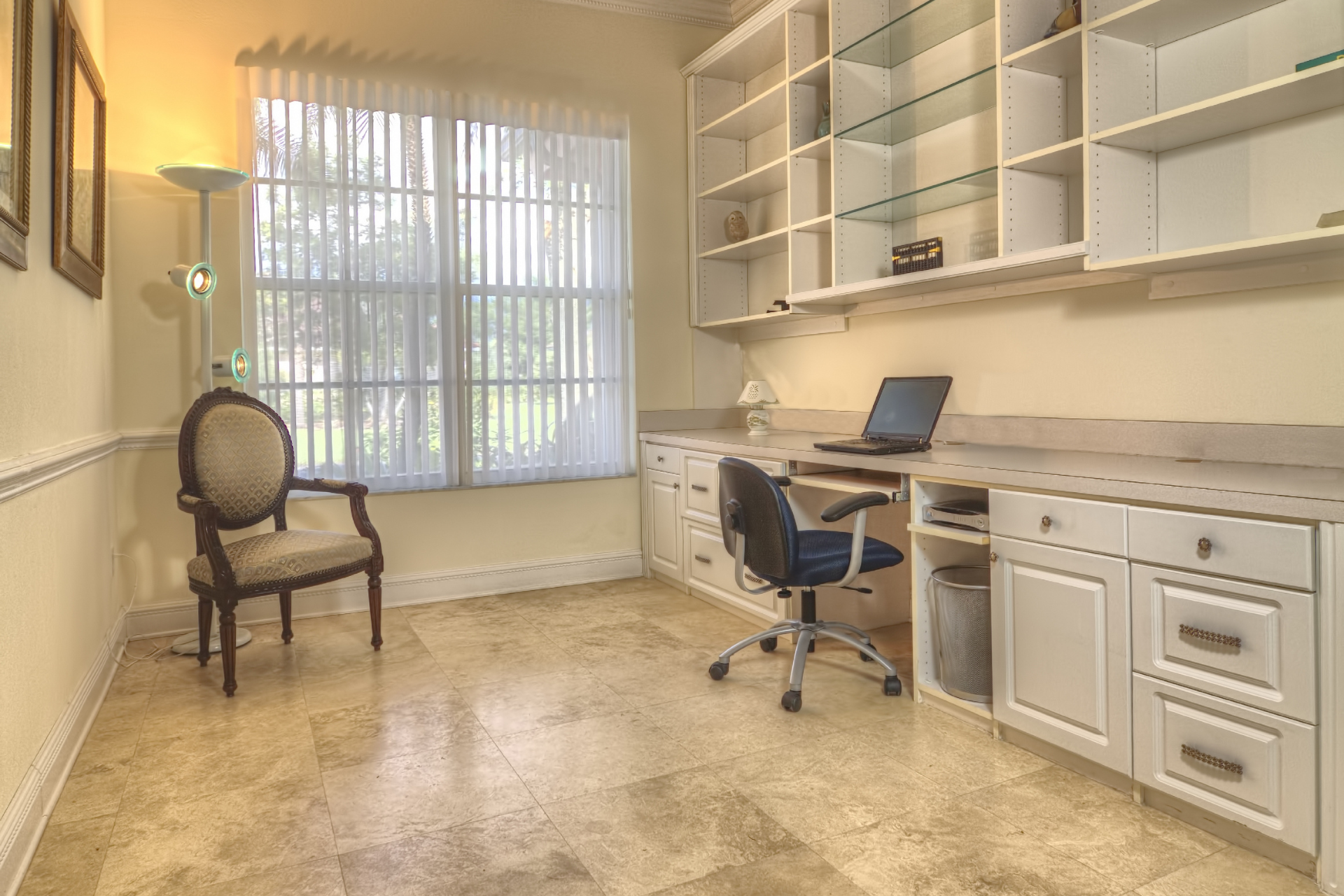 A home office with a desk, chair, shelves and a laptop.