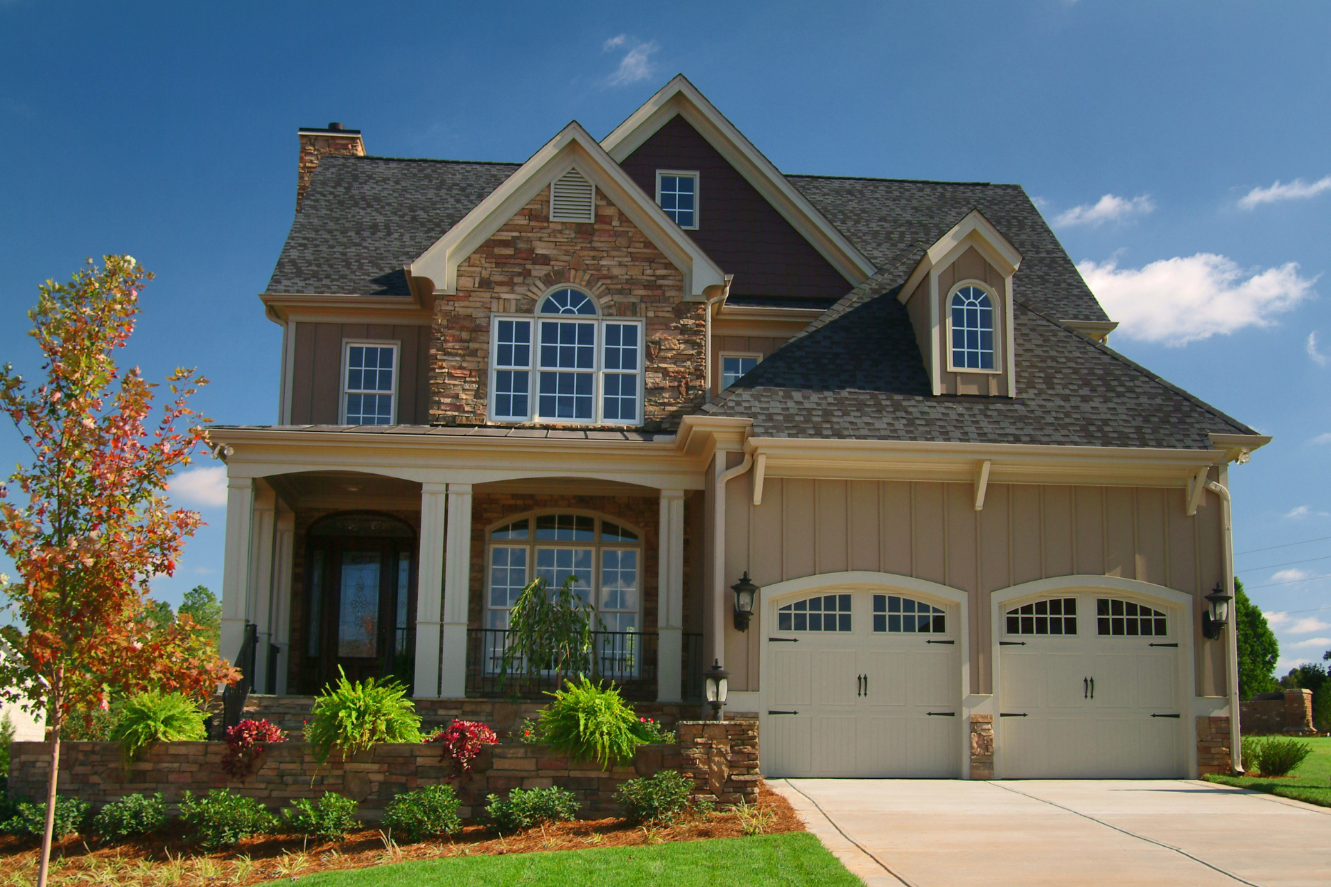 A large custom home with three garage doors on a sunny day