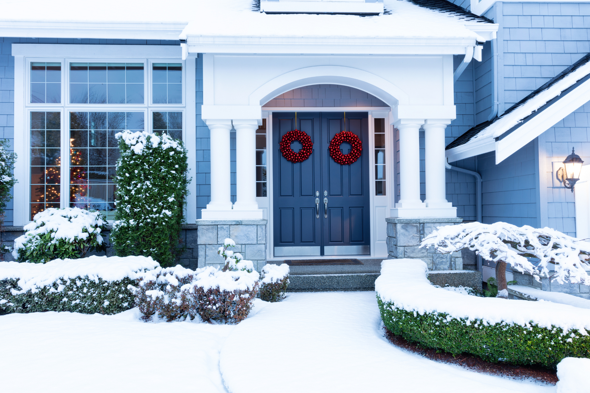 The front door of a house is decorated with christmas wreaths.