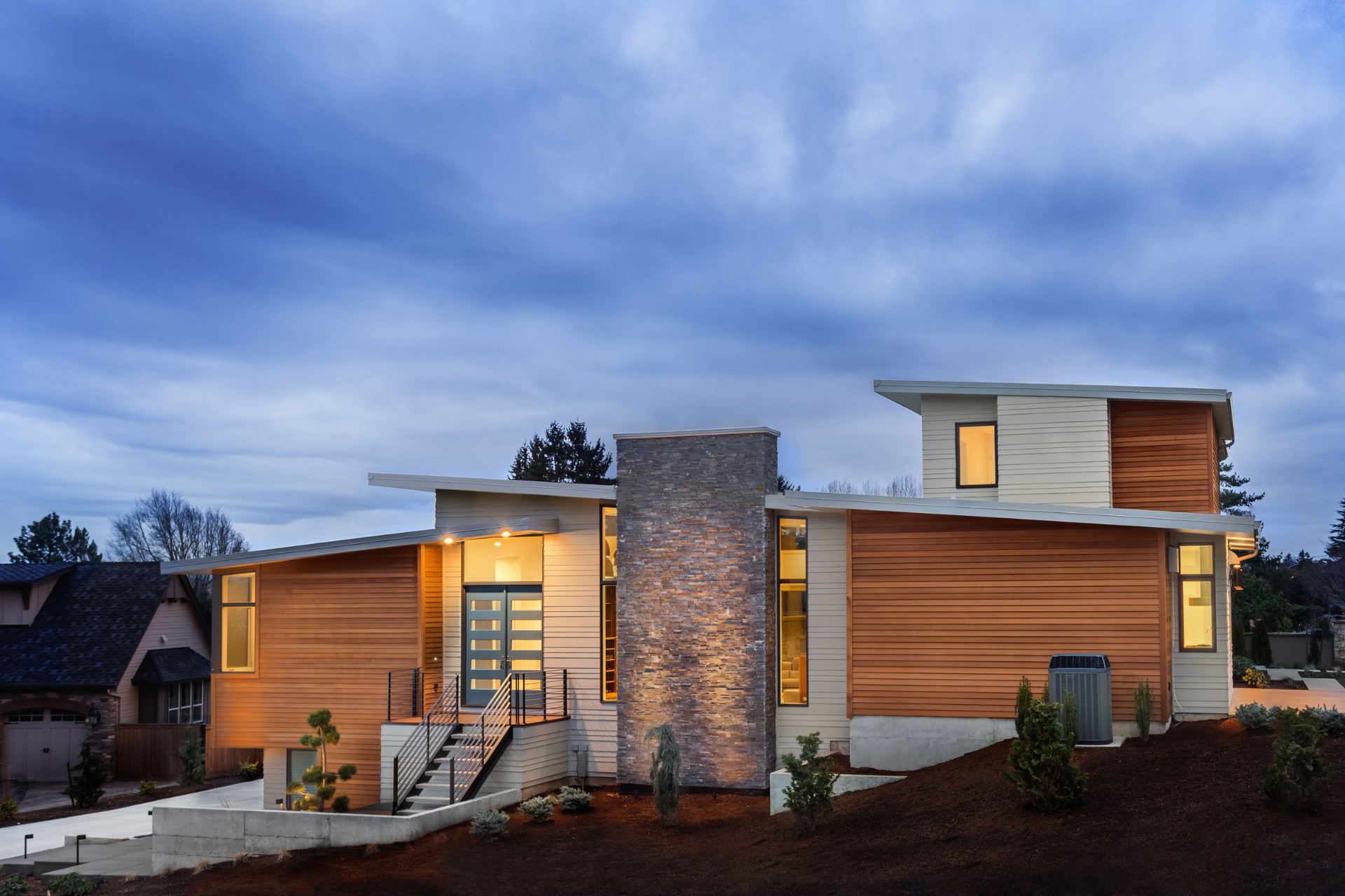 A modern custom home with wood paneling and a stone chimney