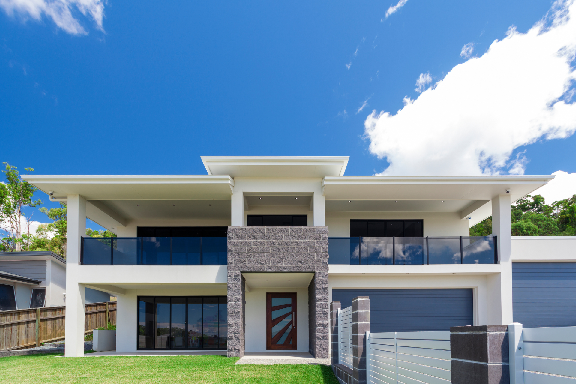 A large white custom home with a blue sky in the background.