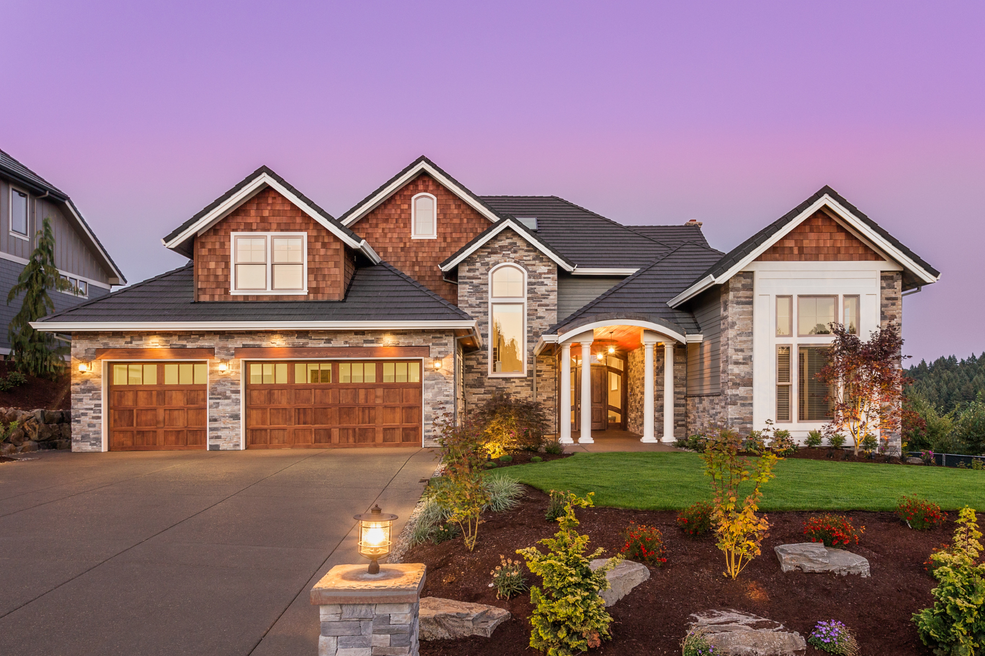 A large brick and stone custom home with a purple sky in the background.