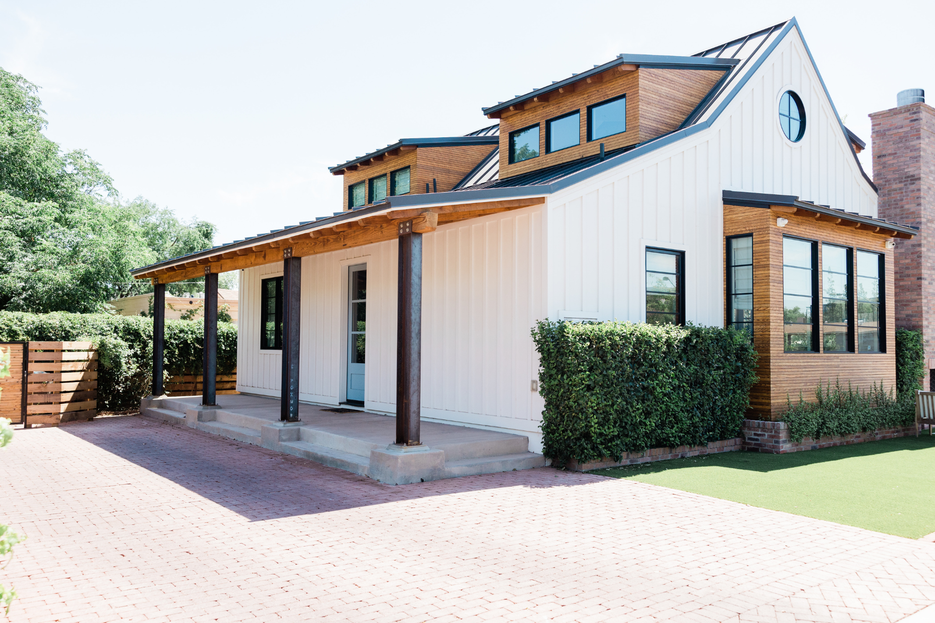 A white custom home with a wooden roof and a porch.