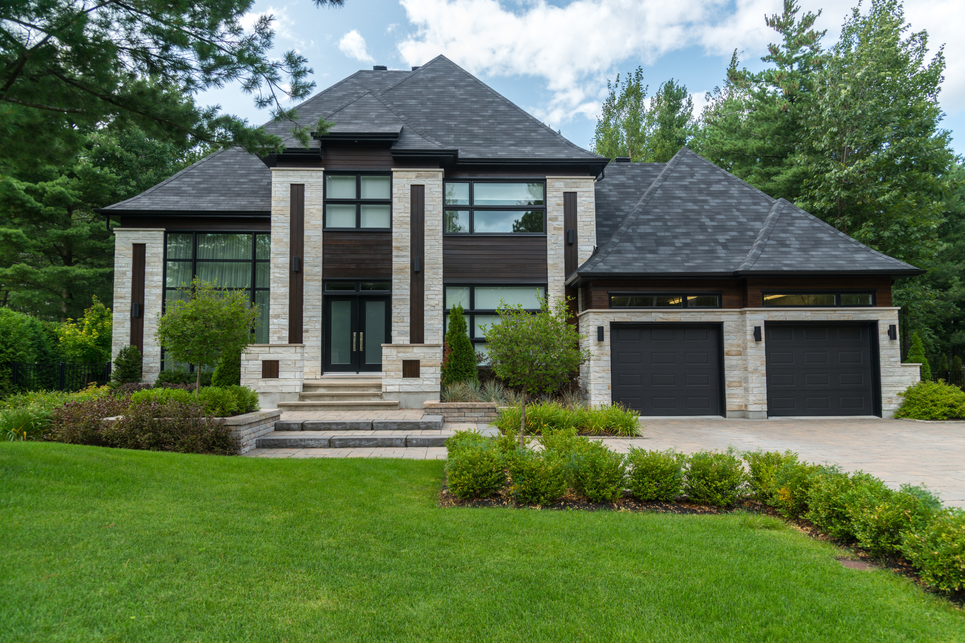 A large custom home with two garages is sitting on top of a lush green lawn.