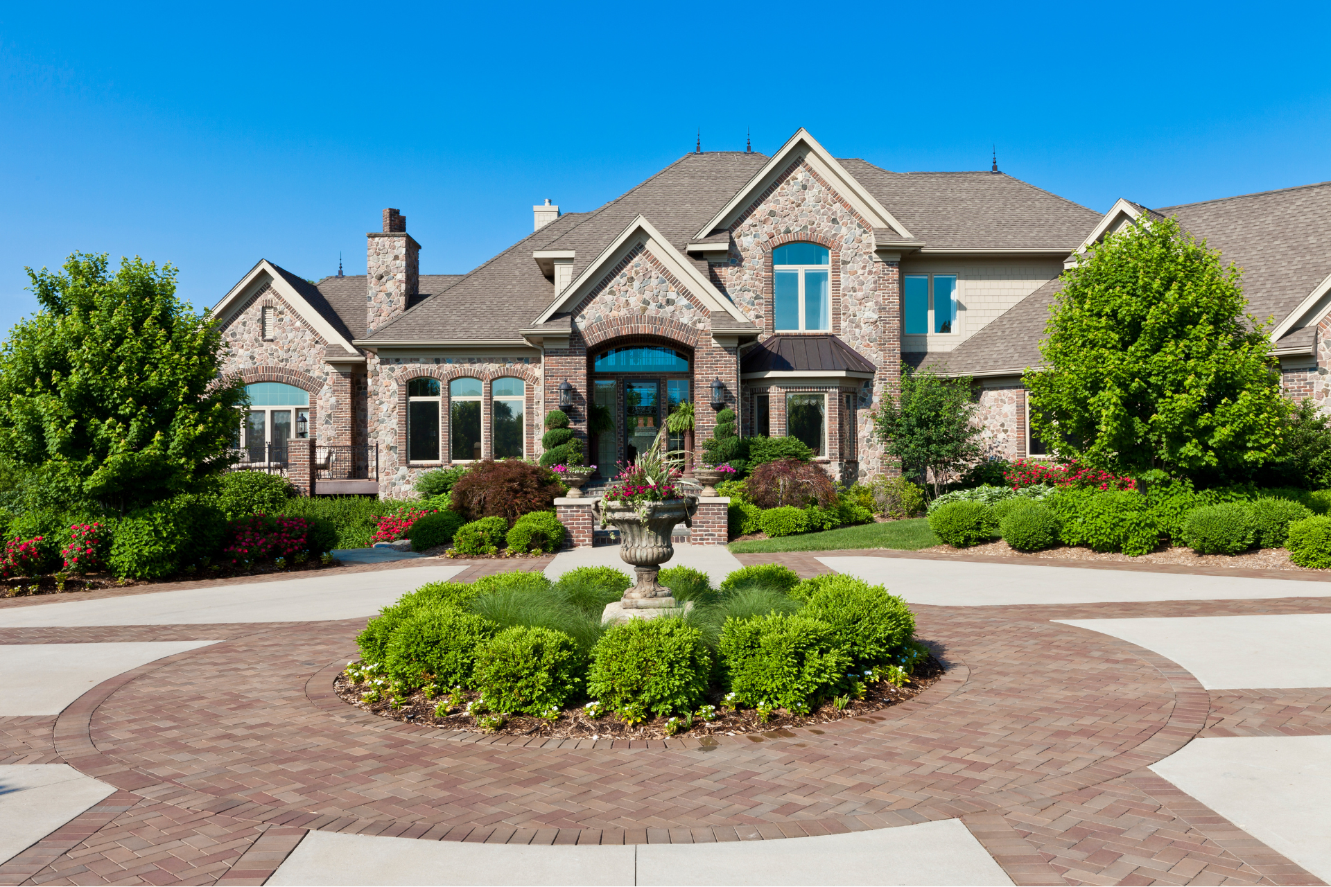 A large custom home with a fountain in front of it
