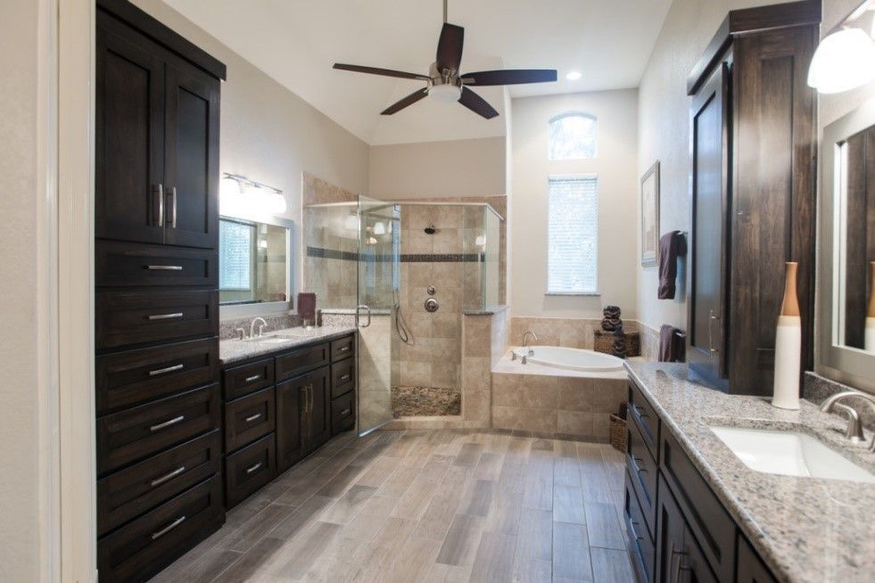 A bathroom with two sinks, a tub and a ceiling fan.