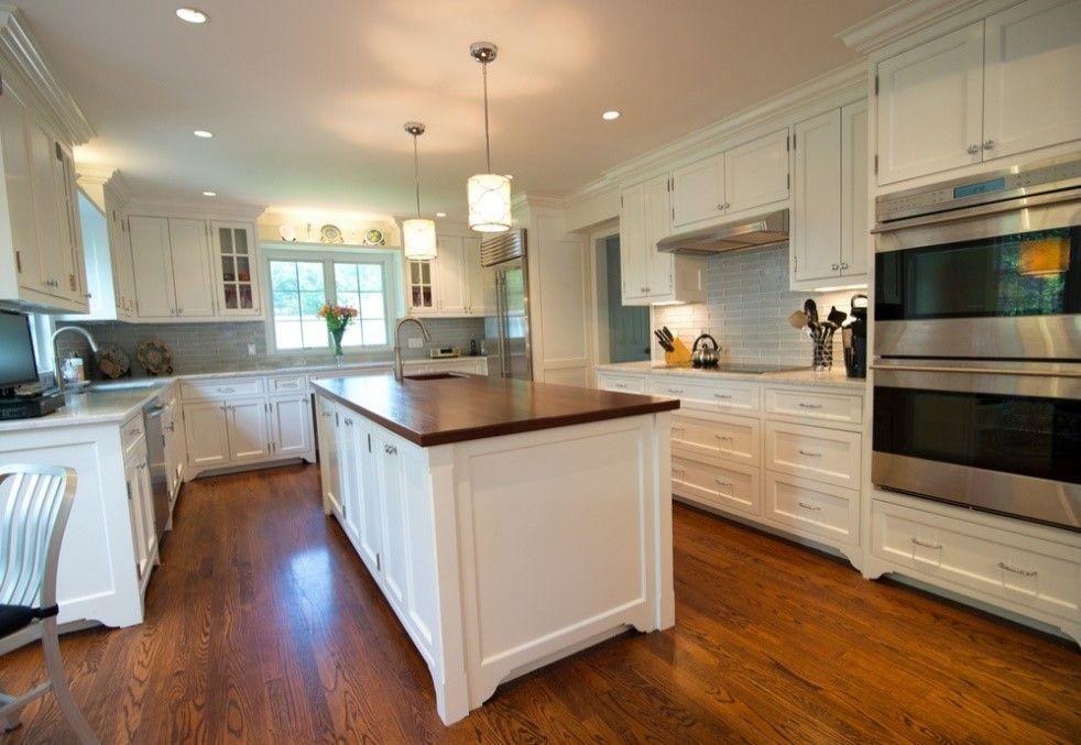 A kitchen with white cabinets and stainless steel appliances and a large island in the middle.
